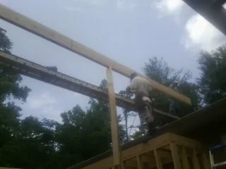 Carpenter setting a ridge beam over a new addition frame — Ice Dam Removal by Roofing Brothers in Eighty Four