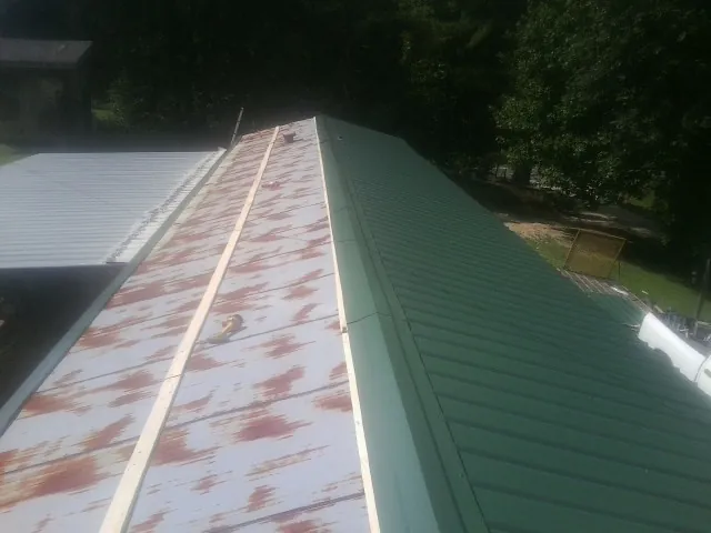 Old rusted panels beside newly installed green metal roofing — Wind Damage Roof Repair by Roofing Brothers in Eighty Four