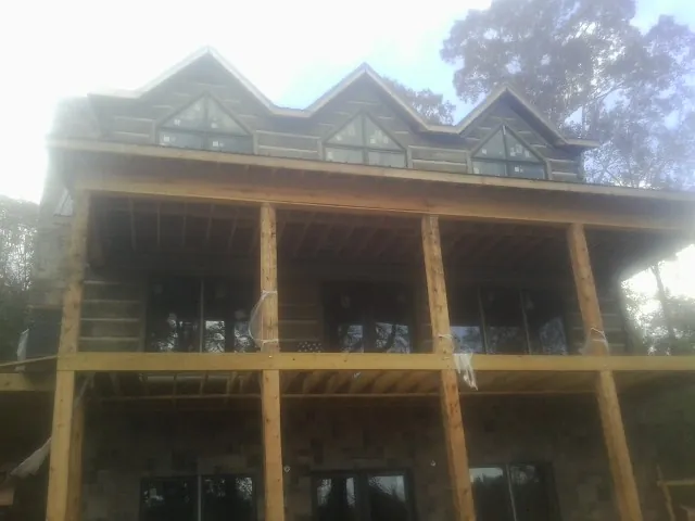 Dormers and porch framing on a large log home under construction — Roof Coating work by our crew in Eighty Four
