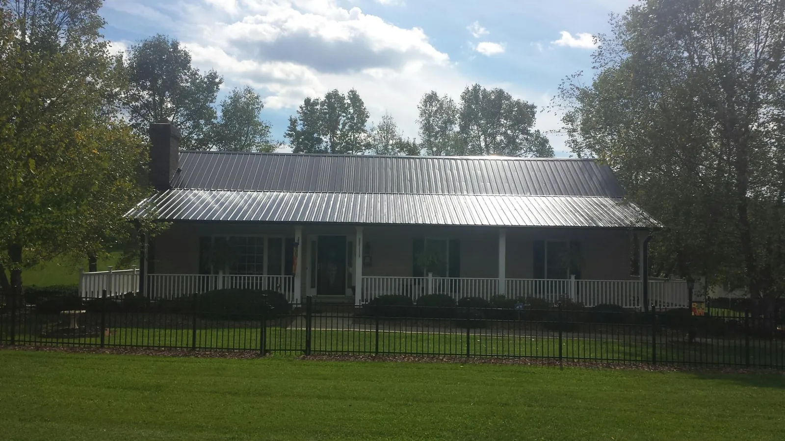 Gray metal roof on a brick ranch with a full width front porch — Gutter Guard Installation work by our crew in Eighty Four