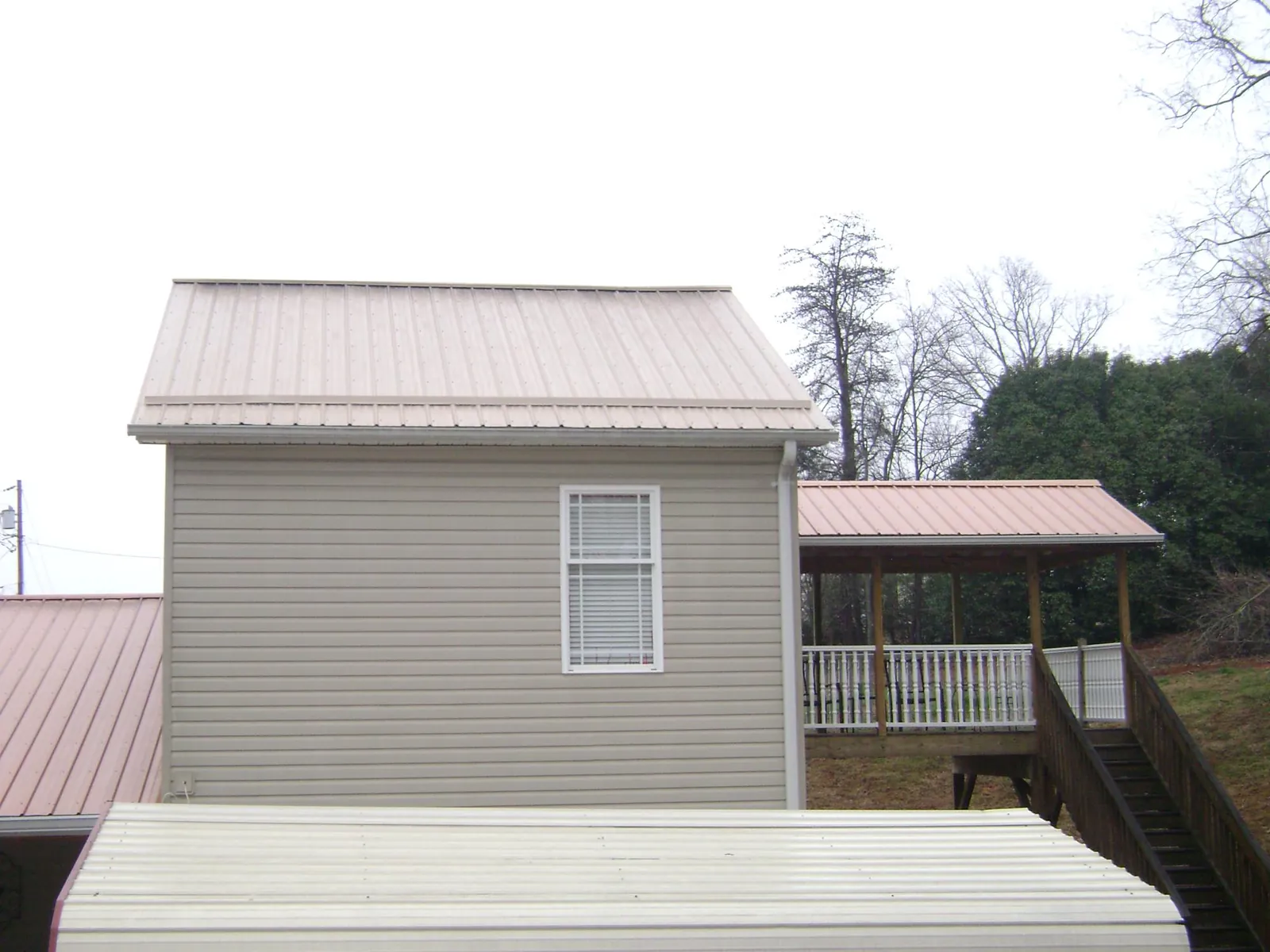 Tan metal roofs on a two story addition and attached porch, from a Roof Replacement job in Eighty Four